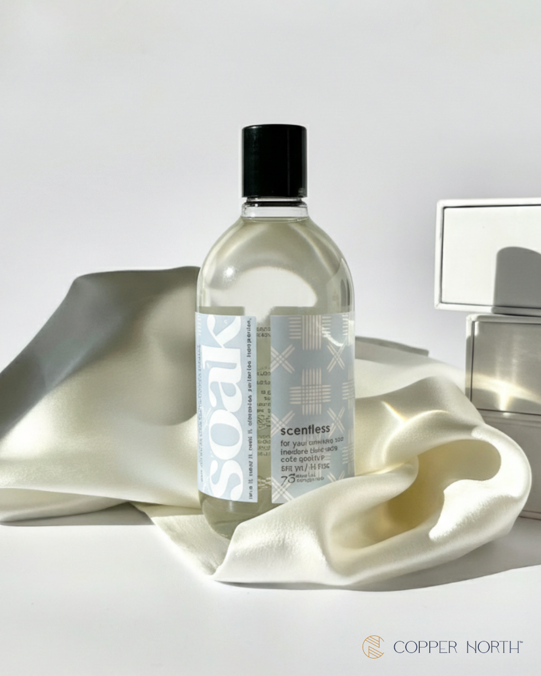 Bottle of 'Soak Scentless' regular size soap with white Copper North silk background