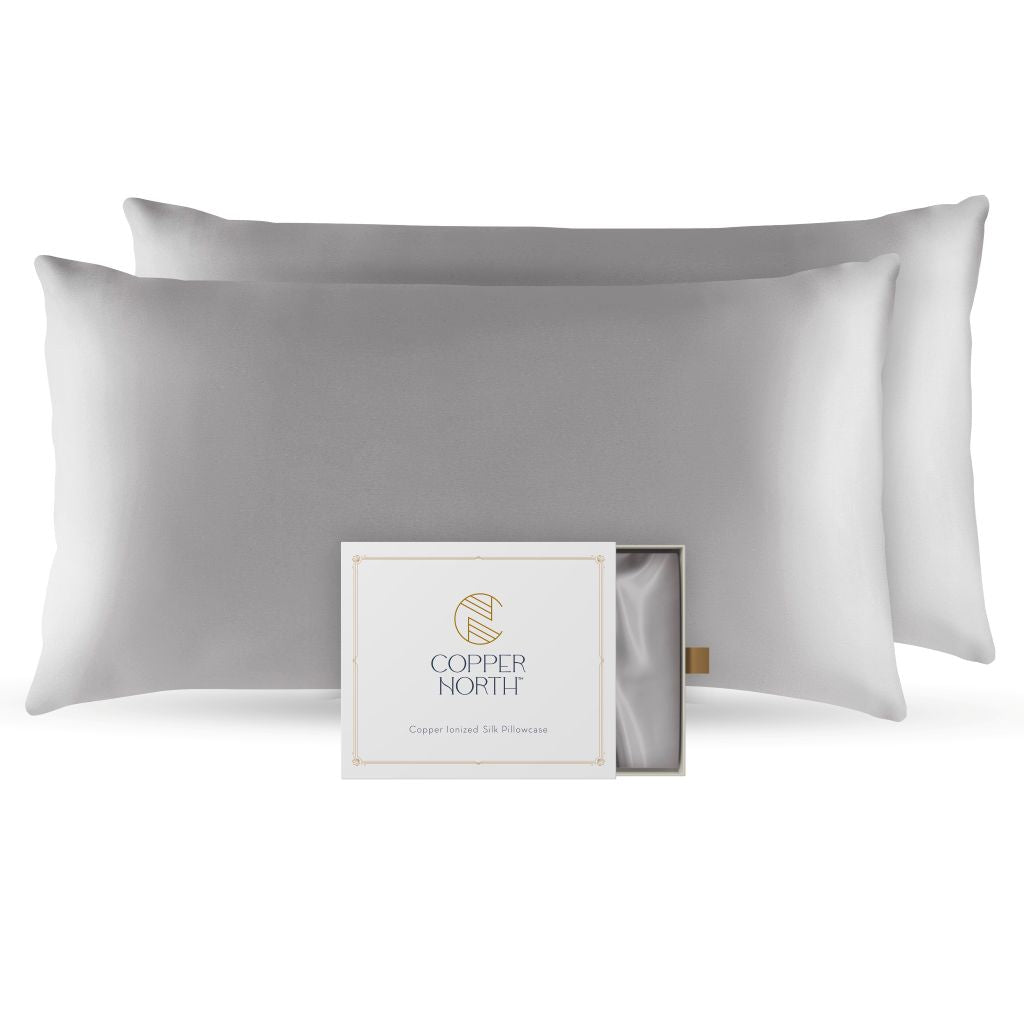 Two gray silk pillowcases with a Copper North packaging box on a white background