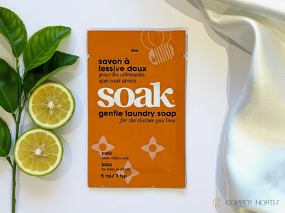 Mini-size of 'soak' gentle laundry soap with yuzus and leaves with white silk on a white background