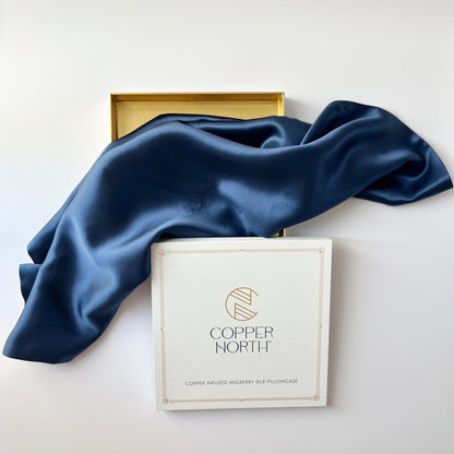 Deep blue silkdraped over a white branded box labeled Copper North, with a gold tray partially visible behind it on a clean white background.