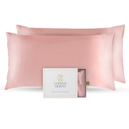 Two rose pink silk pillowcases with a Copper North packaging box on a white background