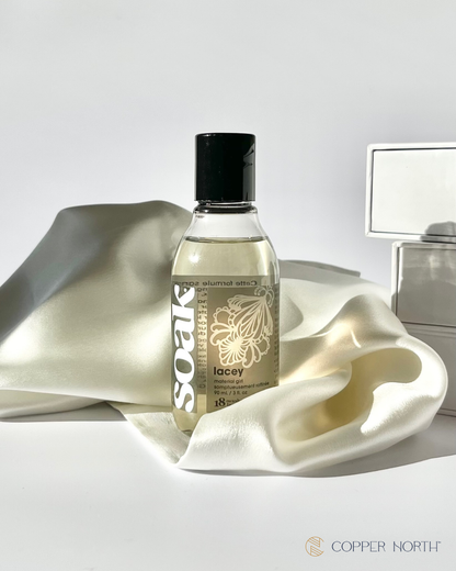 Bottle of 'Soak' laundry detergent with silk pillowcase on a white background