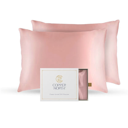 Pink silk pillowcases with a Copper North box on a white background