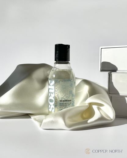 Bottle of 'Soak' detergent with Copper North silk pillowcase with a white background